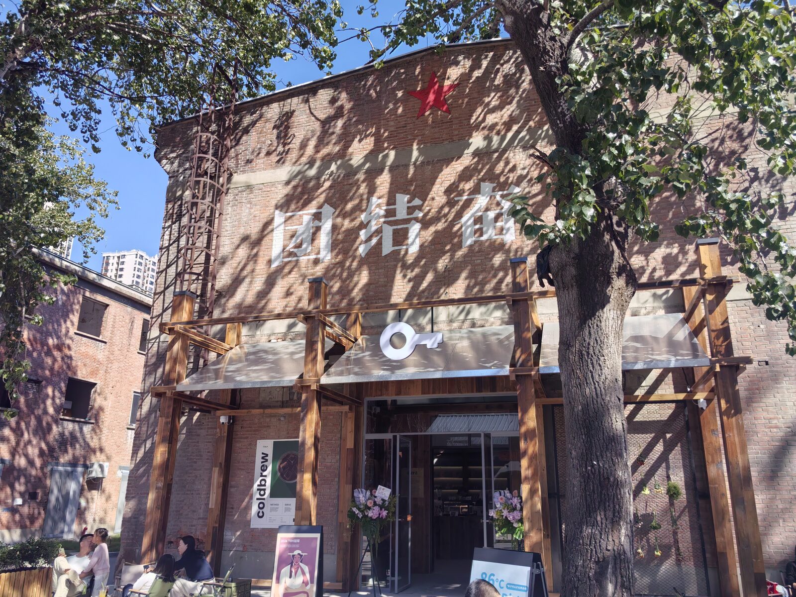 老车间门口,「团结奋斗」四个大字还在,最后一个字被树挡住了